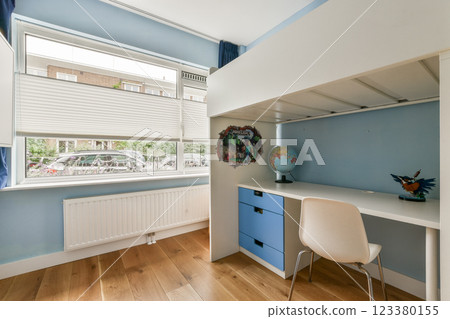 A bright and modern children's bedroom featuring a study space, playful colors, and large windows that invite natural light. 123380155