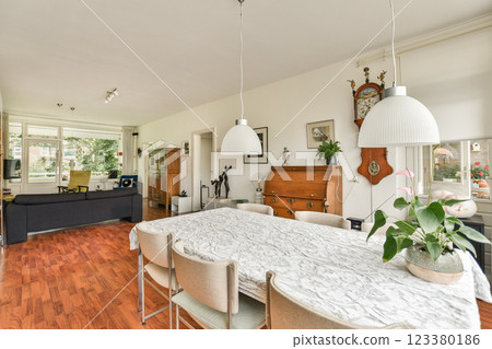 A spacious and bright dining area showcases a modern design, featuring a stylish table with chairs, plants, and warm wooden accents. A spacious and bright dining area showcases a modern design, featuring a stylish table with chairs, plants, and warm wooden accents. 123380186