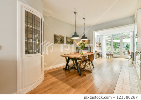 Stylish dining area featuring a wooden table, contemporary chairs, and large windows for ample natural light, creating a warm atmosphere. Stylish dining area featuring a wooden table, contemporary chairs, and large windows for ample natural light, creating a warm atmosphere. 123380267