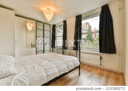 A stylish and minimalistic bedroom showcasing a sleek bed, elegant lighting, and large windows, promoting a serene and inviting atmosphere. A stylish and minimalistic bedroom showcasing a sleek bed, elegant lighting, and large windows, promoting a serene and inviting atmosphere. 123380272