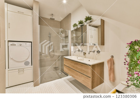 A sleek and contemporary bathroom featuring elegant fixtures, a shower area, and integrated laundry, creating a functional yet aesthetic space. 123380306