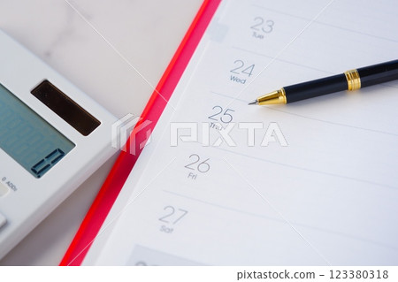 這張照片顯示某人正在查看日曆,點擊計算器,期待 25 日的發薪日。 這張照片顯示某人正在查看日曆,點擊計算器,期待 25 日的發薪日。 123380318