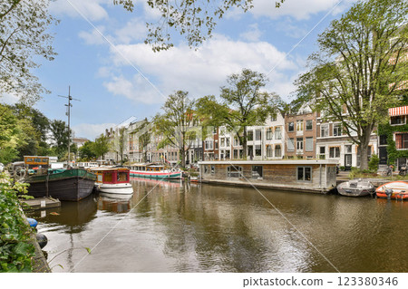 A picturesque canal scene featuring colorful houseboats alongside tree-lined streets, showcasing the charm of urban waterways. 123380346