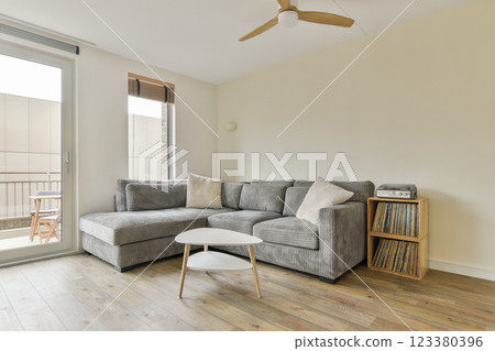 A stylish and modern living room featuring a striped sofa, a round coffee table, and a warm wooden floor, creating a cozy atmosphere for relaxation and entertainment. 123380396