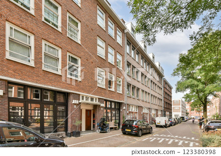 A picturesque urban scene showcasing red brick buildings lining a quiet street, with parked cars and lush greenery adding to the charm of the neighborhood. 123380398