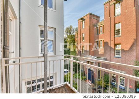 A vibrant view of a modern urban balcony, showcasing neighboring brick buildings and green surroundings under a clear blue sky. A vibrant view of a modern urban balcony, showcasing neighboring brick buildings and green surroundings under a clear blue sky. 123380399