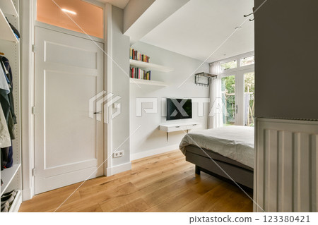 A contemporary bedroom showcasing wooden flooring, a minimalist aesthetic, and abundant natural light from large windows creating a serene atmosphere. 123380421