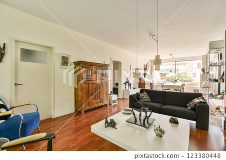 An elegantly designed modern living room showcasing minimalist furniture, wooden flooring, and ample natural light from large windows. An elegantly designed modern living room showcasing minimalist furniture, wooden flooring, and ample natural light from large windows. 123380448