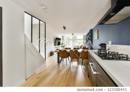 A stylish open-concept kitchen and living area showcasing contemporary design, natural light, and a harmonious color palette. A stylish open-concept kitchen and living area showcasing contemporary design, natural light, and a harmonious color palette. 123380451
