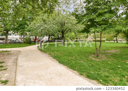 A tranquil pathway curves through a verdant park, lined with vibrant trees and well-maintained grass, inviting leisurely strolls and peaceful reflections. A tranquil pathway curves through a verdant park, lined with vibrant trees and well-maintained grass, inviting leisurely strolls and peaceful reflections. 123380452