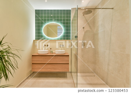 A sleek and contemporary bathroom design featuring green tiles, wooden accents, and modern fixtures. The layout emphasizes natural light and simplicity. 123380453