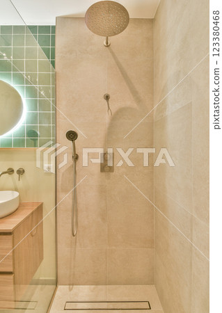 A stylish bathroom featuring a sleek shower design with contemporary tiles, a circular light fixture, and a minimalist aesthetic that enhances relaxation. A stylish bathroom featuring a sleek shower design with contemporary tiles, a circular light fixture, and a minimalist aesthetic that enhances relaxation. 123380468