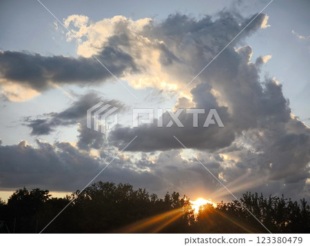 The background of the sunset sky landscape is the natural color of the evening cloudy landscape with the light of the setting sun penetrating through. 123380479