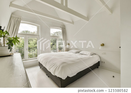 A sleek and bright bedroom featuring large windows that flood the space with natural light, complemented by minimalist decor and a serene atmosphere. 123380582