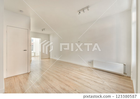 A bright and spacious modern interior featuring light-colored wooden flooring and simple design elements. The room is empty, highlighting its clean lines. 123380587