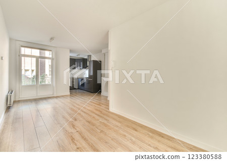 An interior space showcasing a modern minimalist design with light wood flooring, large windows, and a spacious layout, emphasizing natural light. 123380588