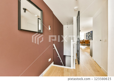 A contemporary hallway showcasing a blend of minimalistic design and modern decor elements, featuring wooden flooring and a stylish mirror. 123380615