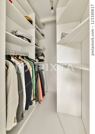 A contemporary closet featuring neatly arranged clothing on shelves, showcasing a clean and minimalist design aesthetic perfect for any wardrobe setup. 123380617