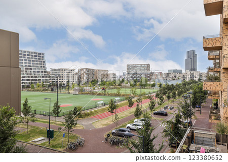 A vibrant urban scene showcasing modern architecture alongside expansive green fields and pathways, ideal for recreational activities. 123380652