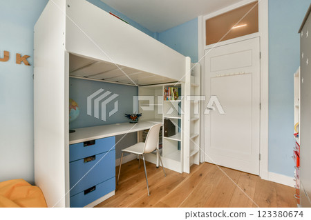 A stylish modern bedroom featuring a loft bed, minimalist study desk, and vibrant colors, creating an inviting and functional living space for comfort and creativity. 123380674