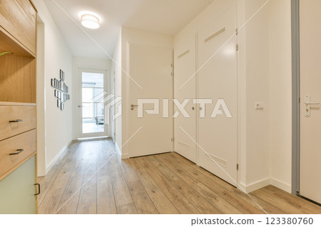 A sleek, modern hallway featuring light-colored walls, wooden flooring, and minimalist design elements that create an inviting atmosphere. A sleek, modern hallway featuring light-colored walls, wooden flooring, and minimalist design elements that create an inviting atmosphere. 123380760