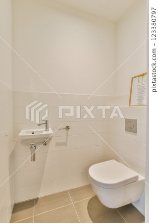 A clean and minimalistic bathroom featuring a modern toilet and sink against white tiled walls. The design emphasizes simplicity and functionality. A clean and minimalistic bathroom featuring a modern toilet and sink against white tiled walls. The design emphasizes simplicity and functionality. 123380797