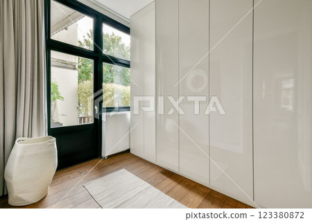 A sleek modern interior featuring large windows that invite natural light, complemented by minimalistic furniture and warm wooden flooring. A sleek modern interior featuring large windows that invite natural light, complemented by minimalistic furniture and warm wooden flooring. 123380872