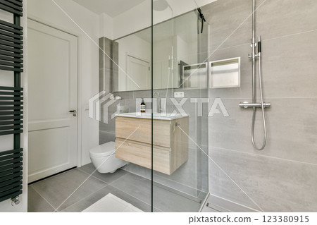 A sleek and contemporary bathroom showcasing a glass shower, wooden vanity, and elegant fixtures for a stylish and functional space. 123380915