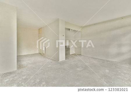 A spacious interior showing a minimalistic design with unfinished walls and a bare floor, reflecting a modern renovation in progress. 123381021