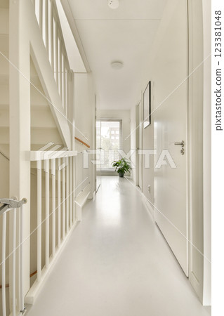 A bright and minimalist hallway featuring a stairway, white walls, and natural light. The decor is simple yet elegant, enhancing the spacious feel of the area. A bright and minimalist hallway featuring a stairway, white walls, and natural light. The decor is simple yet elegant, enhancing the spacious feel of the area. 123381048