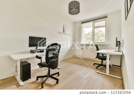 A bright and airy home office featuring two desks, modern chairs, and natural light entering through the window, promoting a productive atmosphere. 123381056