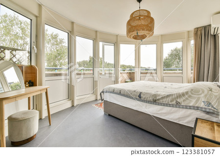 A stylish bedroom featuring large windows that allow ample natural light, complemented by minimalist furniture and a warm atmosphere. A stylish bedroom featuring large windows that allow ample natural light, complemented by minimalist furniture and a warm atmosphere. 123381057