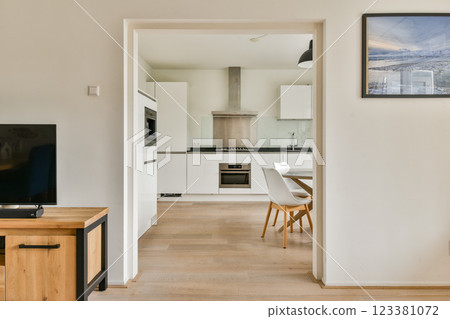 A sleek and modern kitchen featuring minimalist cabinetry, stylish appliances, and an inviting dining area. The open design enhances functionality and space. 123381072