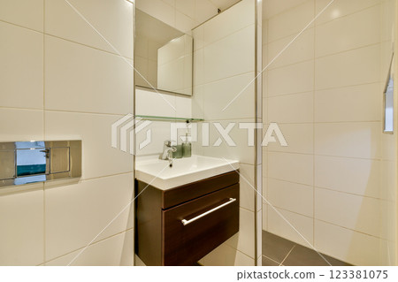 A sleek and contemporary bathroom featuring a clear shower area, a stylish sink unit with storage, and modern tiles that enhance the overall aesthetic. 123381075