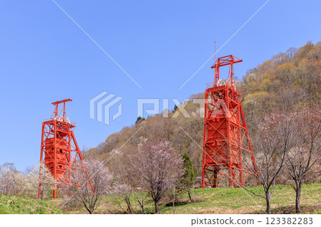 A shaft hoisting machine stands tall in the cherry blossom-filled Coal Mine Memorial Forest Park in Bibai, Hokkaido [May] 123382283