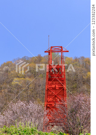 A shaft hoisting machine stands tall in the cherry blossom-filled Coal Mine Memorial Forest Park in Bibai, Hokkaido [May] 123382284