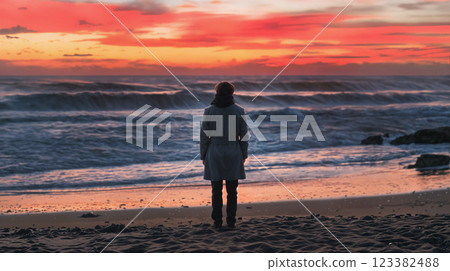 Person standing on beach watching vibrant sunset Person standing on beach watching vibrant sunset 123382488