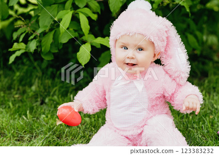 Laughing child at Easter egg hunt baby in pink bunny costume Cute funny girl with Easter eggs and bunny ears at garden. 123383232