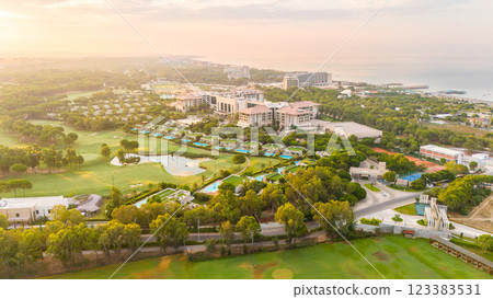 Aerial panoramic view of a luxury seaside resort with golf courses, private villas, and pools at sunrise Aerial panoramic view of a luxury seaside resort with golf courses, private villas, and pools at sunrise 123383531