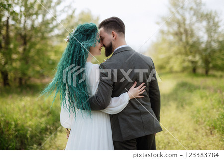 a bearded groom and a girl with green hair are walking a bearded groom and a girl with green hair are walking 123383784