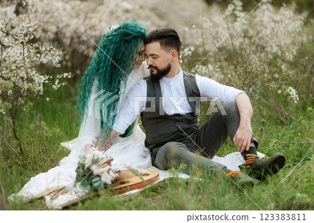 a bearded groom plays a stringed instrument and a girl sits in a spring meadow 123383811