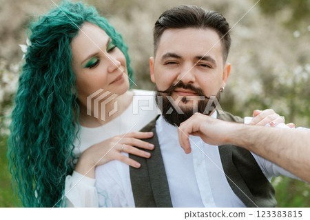 a bearded groom plays a stringed instrument and a girl sits in a spring meadow 123383815