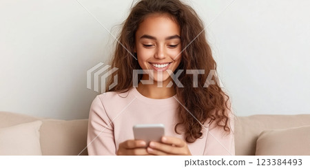 Happy young woman using smartphone at home, smiling and relaxed 123384493