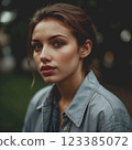 Young woman with dark brown hair. Deep, intense gaze of dark eyes. Woman's hair is combed back. Dressed in a casual style.  123385072