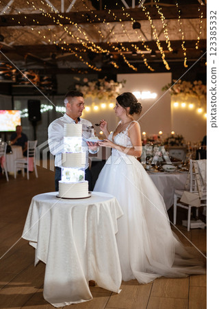 newlyweds happily cut and taste the wedding cake 123385332