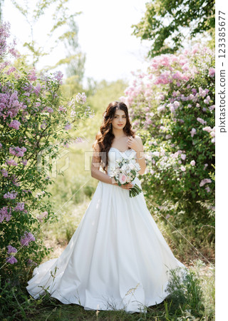 young girl bride in a white dress in a spring forest in lilac bushes 123385677