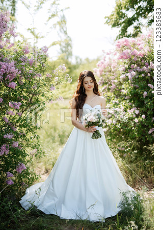 young girl bride in a white dress in a spring forest in lilac bushes young girl bride in a white dress in a spring forest in lilac bushes 123385683