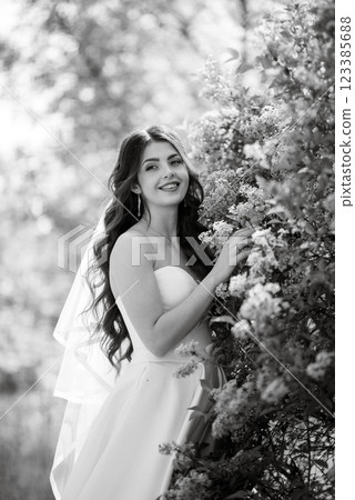 young girl bride in a white dress in a spring forest in lilac bushes young girl bride in a white dress in a spring forest in lilac bushes 123385688