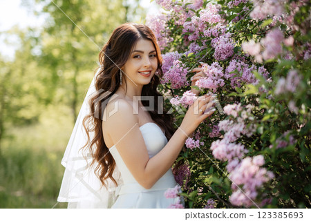 young girl bride in a white dress in a spring forest in lilac bushes young girl bride in a white dress in a spring forest in lilac bushes 123385693