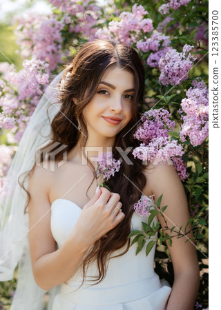young girl bride in a white dress in a spring forest in lilac bushes 123385700